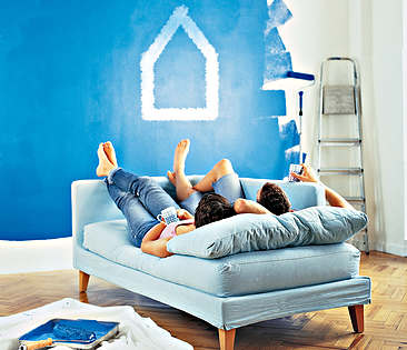 Immobilienfinanzierung - Paar schaut vom Sofa auf gestrichene Wand